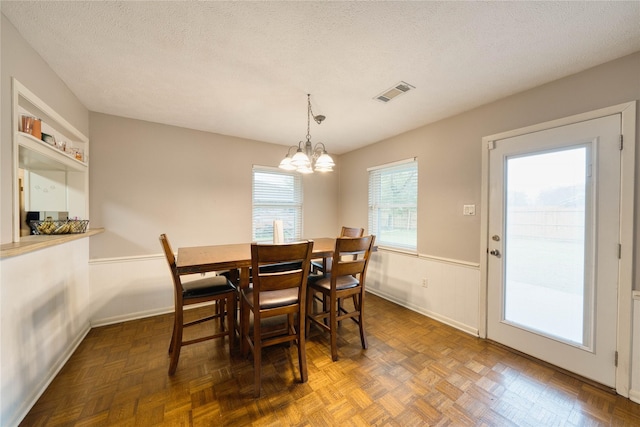 dining area featuring built in features, dark parquet floors, a healthy amount of sunlight, and a textured ceiling