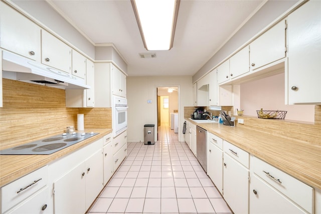 kitchen featuring white oven, dishwasher, washer / dryer, white cabinetry, and electric cooktop