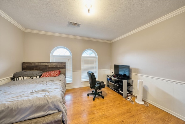 bedroom with light wood-type flooring, crown molding, and a textured ceiling