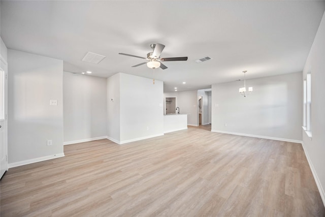 unfurnished living room with ceiling fan with notable chandelier and light hardwood / wood-style floors