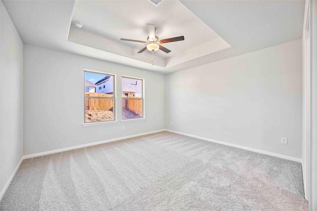 spare room featuring ceiling fan, a raised ceiling, and carpet floors