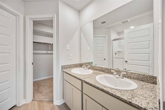 bathroom with wood-type flooring, a shower with door, and vanity