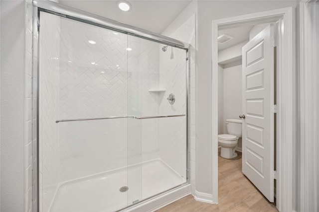 bathroom with hardwood / wood-style flooring, toilet, and an enclosed shower