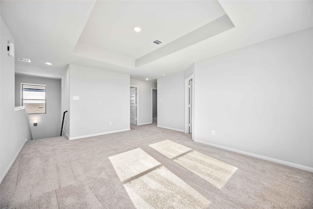 empty room featuring light colored carpet and a raised ceiling