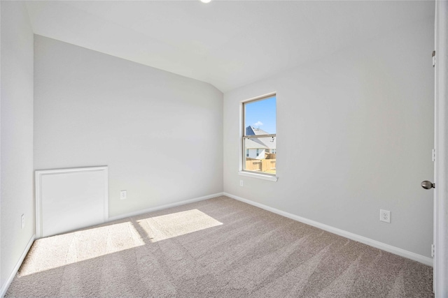 carpeted empty room featuring vaulted ceiling