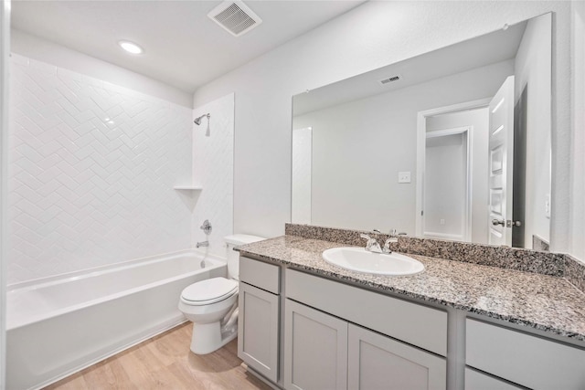 full bathroom featuring hardwood / wood-style flooring, washtub / shower combination, vanity, and toilet