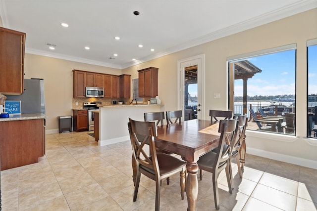 dining area featuring ornamental molding and light tile patterned flooring