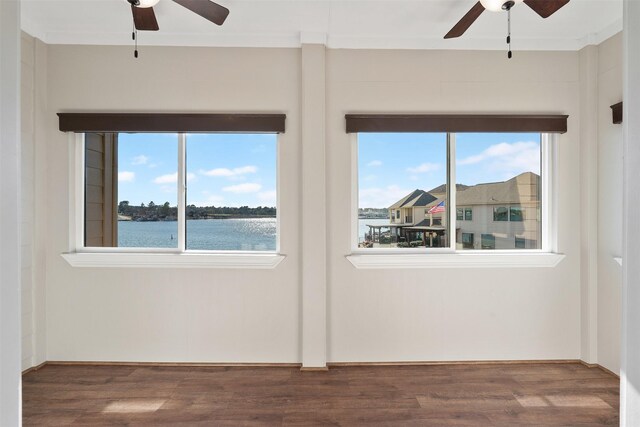 unfurnished room with ceiling fan, a water view, and dark wood-type flooring