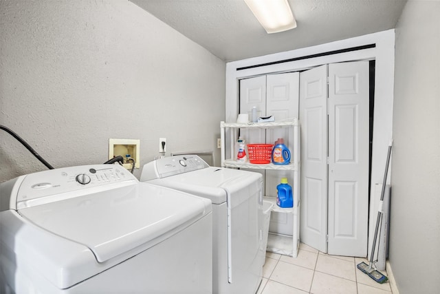 laundry area with light tile patterned floors, a textured ceiling, and washing machine and clothes dryer