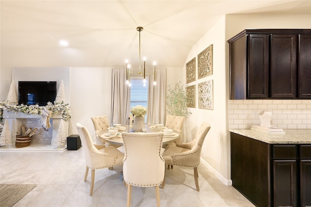 dining space with a chandelier, light tile patterned floors, and lofted ceiling