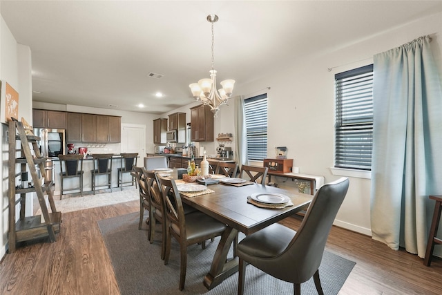 dining space featuring hardwood / wood-style flooring and an inviting chandelier