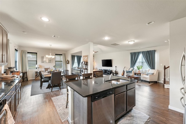 kitchen featuring a notable chandelier, pendant lighting, dark hardwood / wood-style flooring, an island with sink, and stainless steel appliances