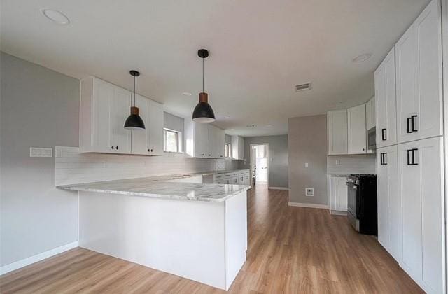 kitchen with stainless steel appliances, white cabinetry, kitchen peninsula, and light hardwood / wood-style floors