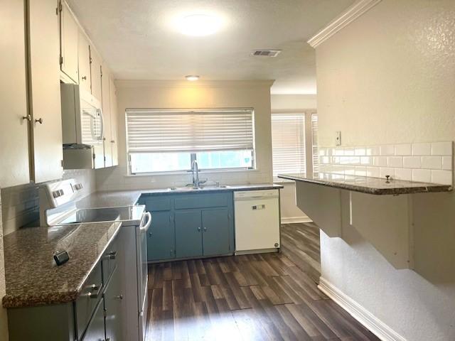 kitchen with crown molding, sink, white appliances, dark hardwood / wood-style floors, and dark stone countertops