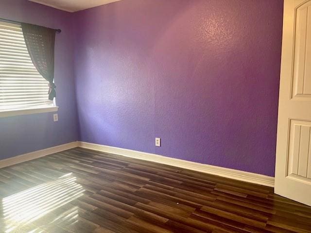 empty room with baseboards and dark wood-type flooring