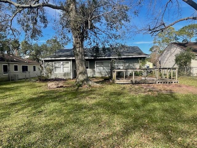 back of property featuring a wooden deck and a yard