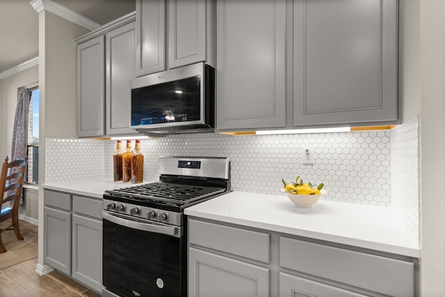 kitchen featuring stainless steel appliances, ornamental molding, gray cabinets, and backsplash