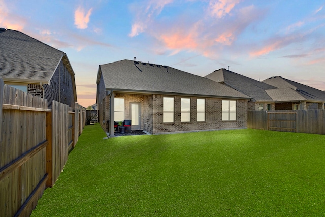 back house at dusk with a lawn