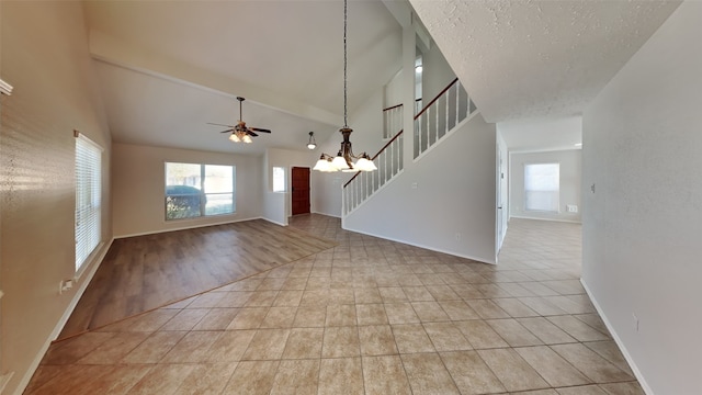 interior space with vaulted ceiling, ceiling fan with notable chandelier, a textured ceiling, and light tile patterned flooring