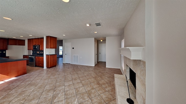 kitchen with a textured ceiling, light tile patterned floors, a high end fireplace, and stainless steel appliances