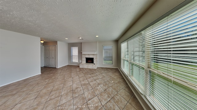 unfurnished living room featuring a textured ceiling, a fireplace, and light tile patterned flooring