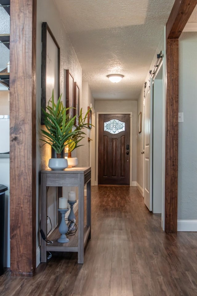 doorway featuring dark wood-type flooring, a textured ceiling, and a barn door