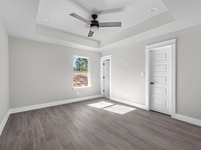 unfurnished room featuring wood-type flooring, ceiling fan, and a raised ceiling