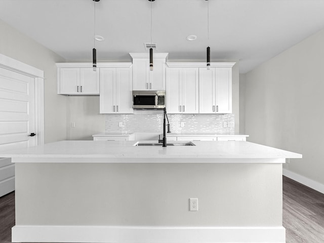 kitchen with sink, decorative light fixtures, and a center island with sink