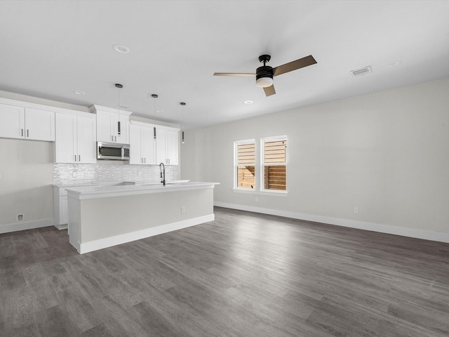 kitchen featuring white cabinetry, dark hardwood / wood-style floors, pendant lighting, and an island with sink