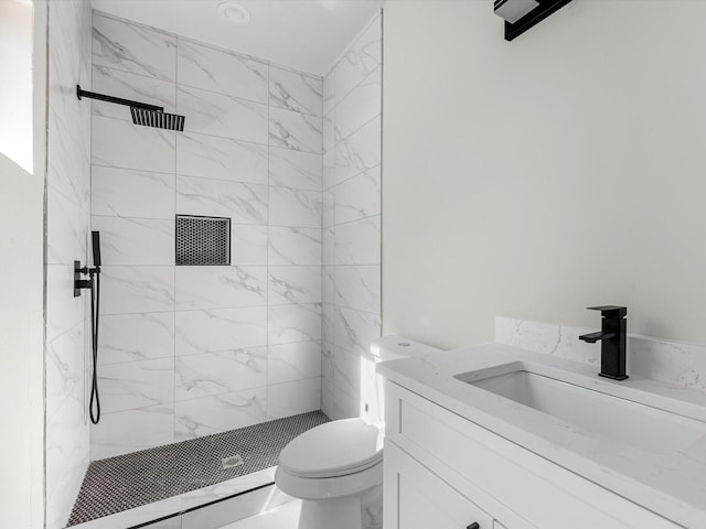 bathroom featuring toilet, tiled shower, and vanity