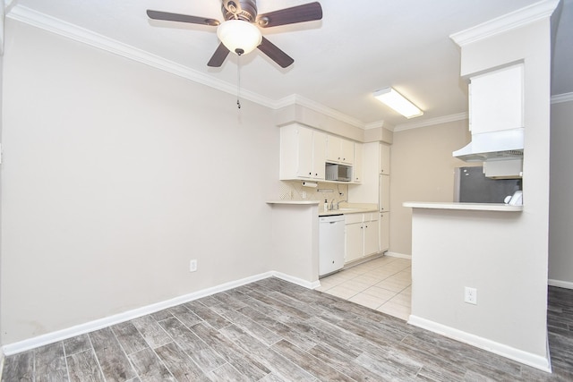 kitchen with white dishwasher, white cabinetry, ornamental molding, and stainless steel refrigerator