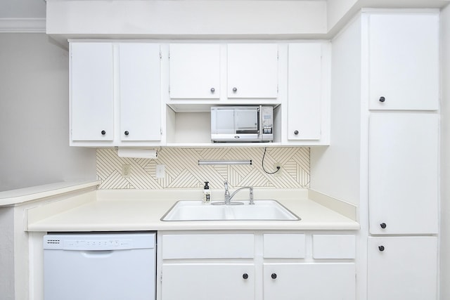 kitchen with white dishwasher, decorative backsplash, sink, white cabinets, and ornamental molding