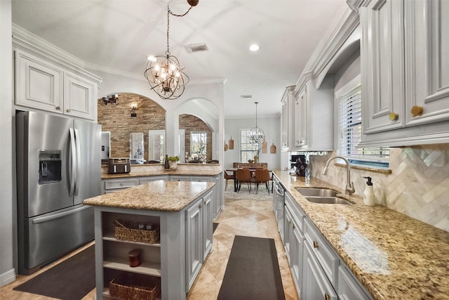 kitchen with a chandelier, sink, decorative light fixtures, ornamental molding, and stainless steel appliances