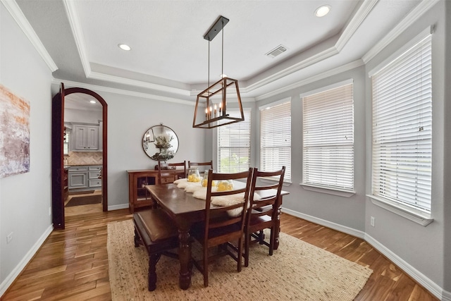 dining area with dark hardwood / wood-style flooring, ornamental molding, and a raised ceiling