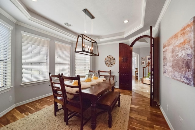 dining room with crown molding, dark hardwood / wood-style floors, and a tray ceiling