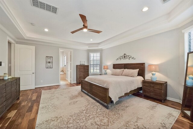 bedroom featuring ceiling fan, dark hardwood / wood-style floors, connected bathroom, and a tray ceiling