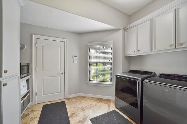 clothes washing area featuring washing machine and clothes dryer and cabinets