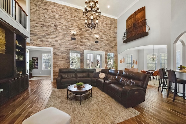 living room with a towering ceiling, a chandelier, ornamental molding, and dark wood-type flooring