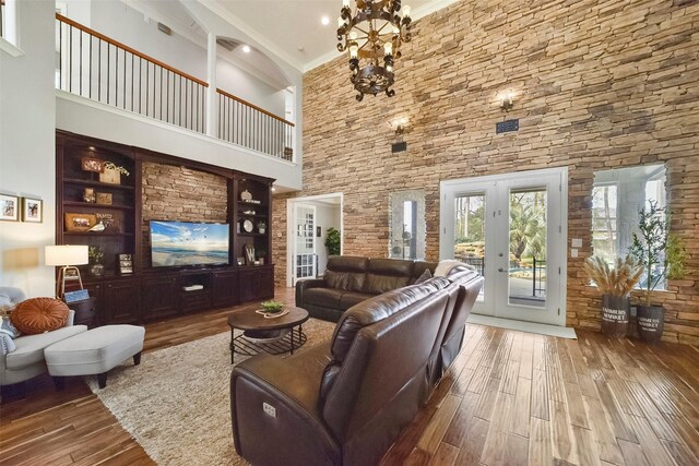 living room featuring wood-type flooring, french doors, built in features, and a towering ceiling