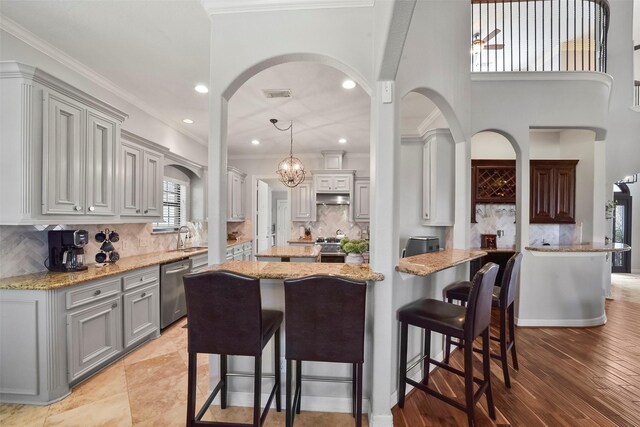 kitchen with backsplash, hanging light fixtures, appliances with stainless steel finishes, and a kitchen breakfast bar