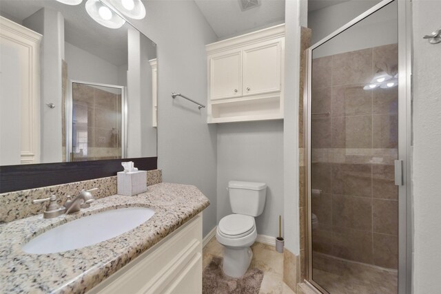 bathroom featuring toilet, a shower with shower door, and vanity