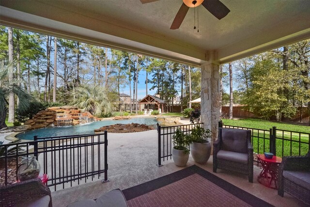 view of patio / terrace with a fenced in pool, ceiling fan, and pool water feature