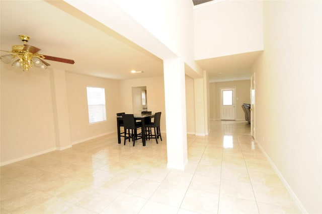 interior space featuring light tile patterned floors, a ceiling fan, and baseboards