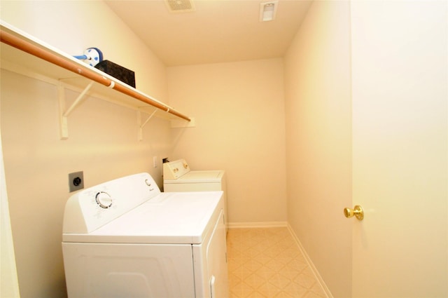 clothes washing area with light floors, visible vents, washer and clothes dryer, and laundry area