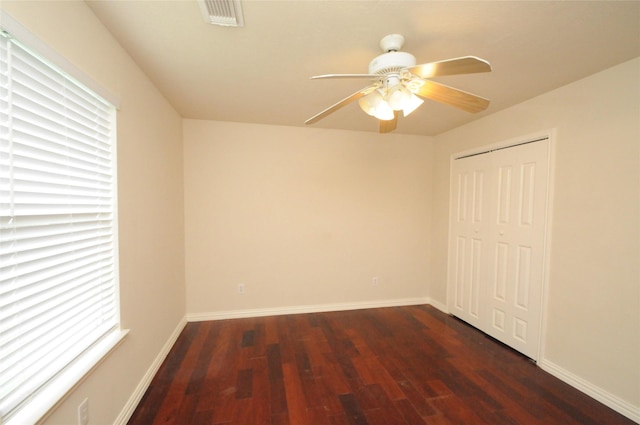 unfurnished room featuring wood finished floors, a ceiling fan, visible vents, and baseboards