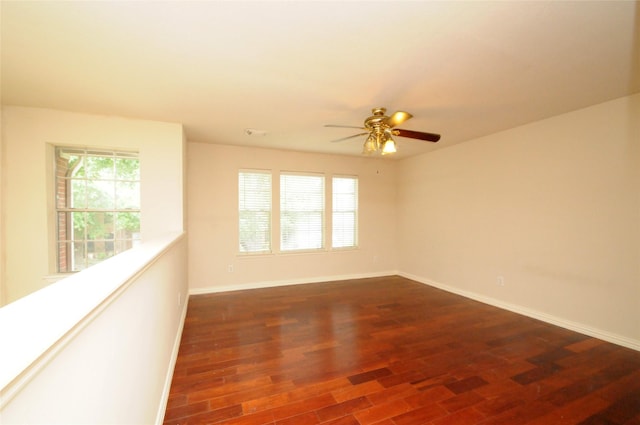 empty room featuring baseboards, ceiling fan, and dark wood-style flooring