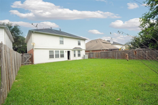 rear view of property with a lawn, central air condition unit, and a fenced backyard