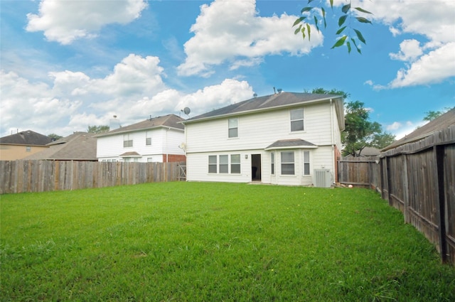 rear view of property featuring a yard, central AC, and a fenced backyard