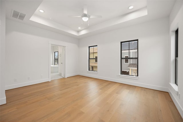 unfurnished room featuring ceiling fan, a raised ceiling, and light hardwood / wood-style flooring