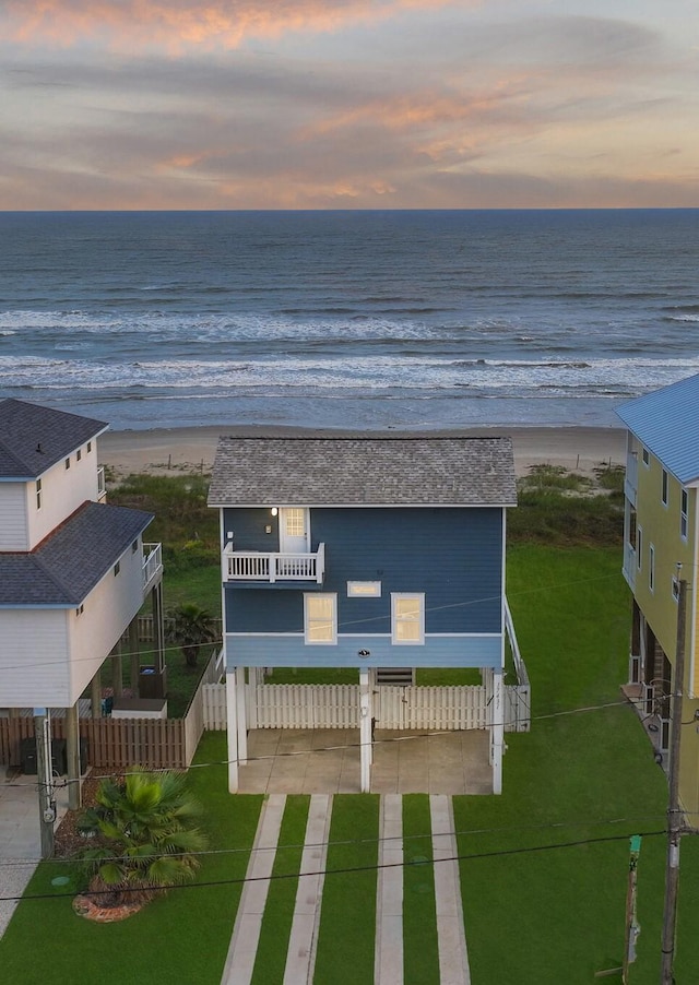 aerial view at dusk featuring a water view and a beach view